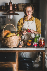 Autumn seasonal vegetable pickling and canning. Young blond woman in linen apron cooking homemade...