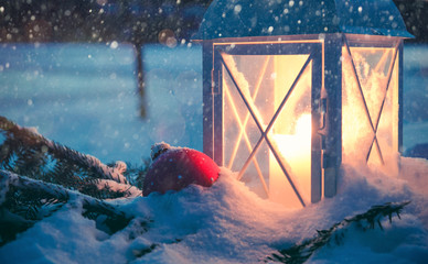 Beautiful old lantern and a red Christmas bauble in winter evening snowfall. This image was taken at Kaarina, Finland.