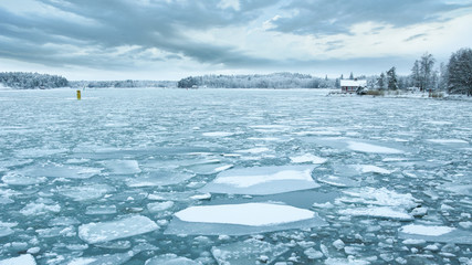 Baltic Sea with ice floes and a typical wooden house by the ice covered coast in Turku, Finland. 