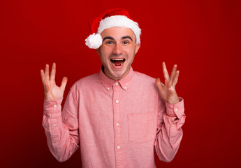 Portrait of amazed screaming man wearing santa claus hat, ready for holidays