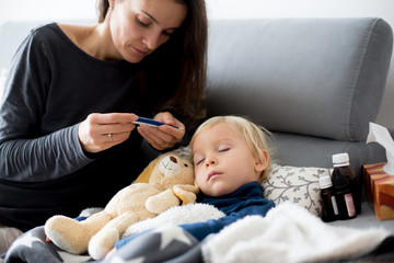 Blond toddler boy, sleeping on the couch in living room, lying down with fever