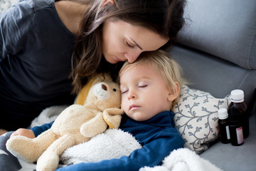 Blond toddler boy, sleeping on the couch in living room, lying down with fever