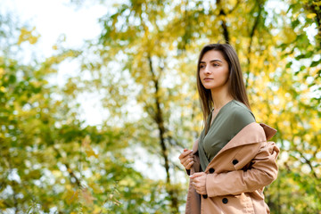 Autumn park. Beautiful woman in green dress posing in autumn park with yellow leaves