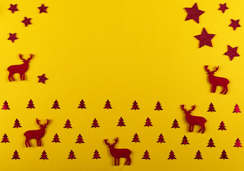 Christmas and New Year composition. Christmas silhouette of deer and fir-trees, red decorations on bright yellow background.  Flat lay with copy space. Top view