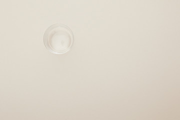 top view of glass with water isolated on beige