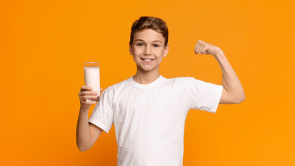 Confident strong teenager enjoying milk and showing his biceps