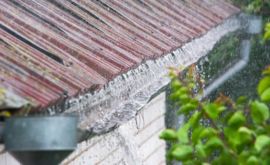Closeup of water overflowing from old gutter during a heavy rainstorm
