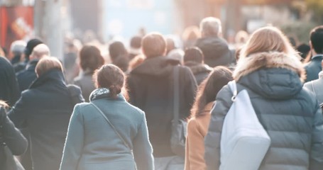 Commuters walking to work with morning sun light in business district, footage of blurred people commuting in downtown from back, busy city life, 4K video