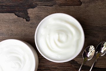 Yogurt greek white clean In bowl with spoon on a wooden background from top view.