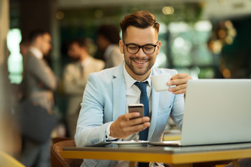 Businessman Using Phone Whilst Working In Coffee Shop