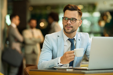 Businessman Using Laptop Whilst Working In Coffee Shop