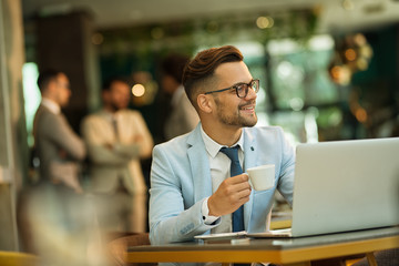 Businessman Using Laptop Whilst Working In Coffee Shop