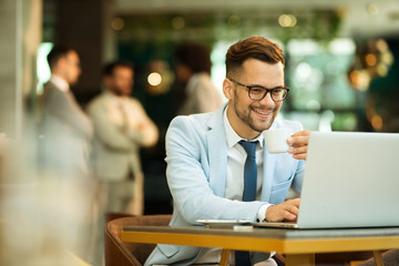 Businessman Using Laptop Whilst Working In Coffee Shop