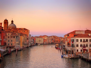 Fototapeta na wymiar the grand canal in venice in glowing evening twilight with sunset sky with reflections of historic buildings and boats