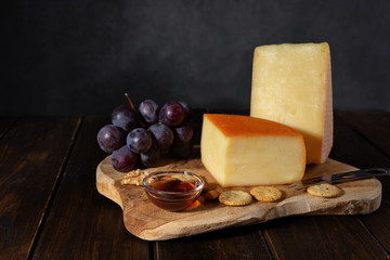 Cheese on a wooden board with nuts and honey