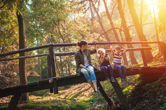 Mother with kids enjoys in sunny autumn day in nature.