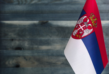 Fragment of the flag of the Republic of Serbia in the foreground blurred wooden background place...
