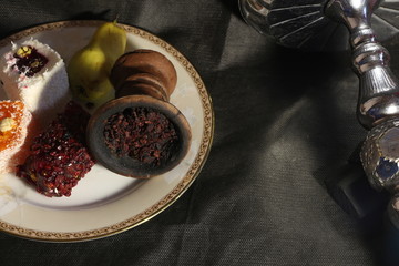 bowl with tobacco for hookah. fruits on a black background. smoking hookah