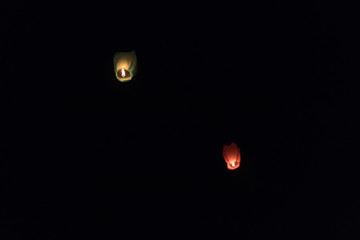 Isolated red and green sky lanterns in black night background with space for text.  The design is good for presentation, website, greeting card related to love, romance, festival, and celebration