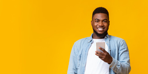 Portrait of smiling black guy with smartphone in hands