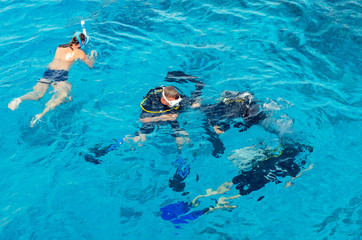 Scuba divers dive into the clear blue water in the sea