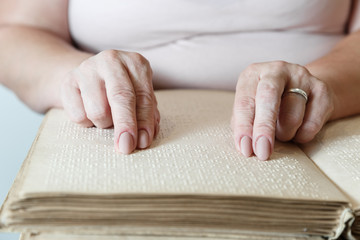 woman reading braille text on old book