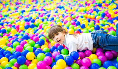 Fototapeta na wymiar Cute girl plays in the pool with plastic balls