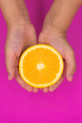 Organic freshness Orange cutting on kid hand Isolated pink background