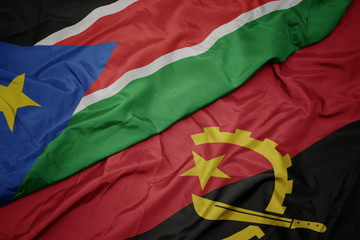 waving colorful flag of angola and national flag of south sudan.