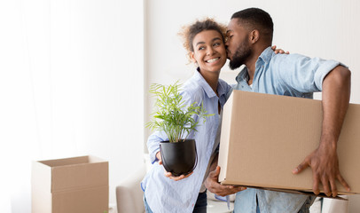 Afro Husband Kissing Wife In Cheek Holding Moving Box Indoor