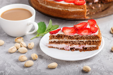 Homemade cake with yoghurt cream, strawberry and pistachio on a gray concrete  background. side view.