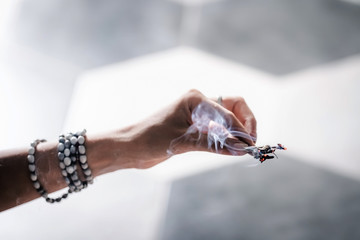 Woman's hands smudging burning sage, dry plant. Space, energy healing. Close up, copy space