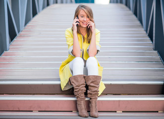 cheerful beautiful woman sitting on the stairs and talking on the mobile phone