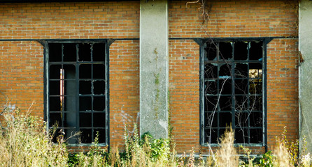 Bâtiment abandonné en brique rouge et fenêtre en métal noir à petits carreaux en verre cassées, grunge