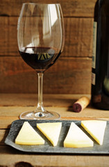 Glass of red wine and cheese on wood
