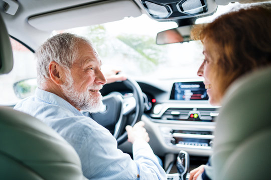 Rear View Of Happy Senior Couple Sitting In Car, Talking.