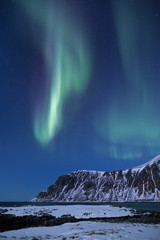 Fototapeta na wymiar Beautiful northern lights over the snow covered winter landscape of the Lofoten islands