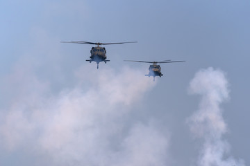 Fototapeta na wymiar American Black Hawk helicopter Sikorsky UH - 60M attack takes off at the operation with weapons between smoke in battle war on the blue sky