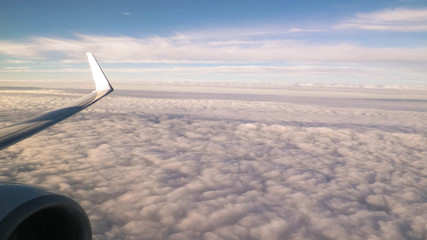 View of white clouds and plane enginie and wing.