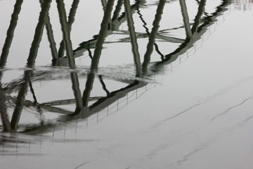 distorted reflection of the bridge structure on the water surface of the cold river