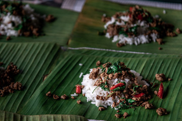 Rice topped with Stir fried Thai basil with minced pork (Pad Ka Prao Moo) on served on a banana leaf.