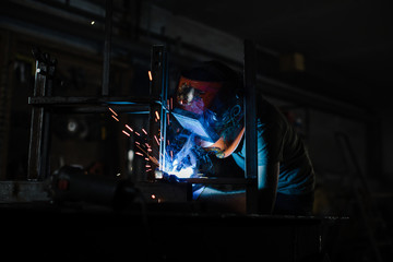A man in a helmet works with a welding machine