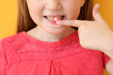 Little girl suffering from toothache on color background, closeup