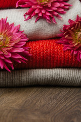 Pattern of colorful knitted sweaters closeup. Handmade merino wool product. A stack of folded clothes with flowers.