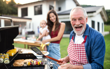 Portrait of multigeneration family outdoors on garden barbecue, grilling.