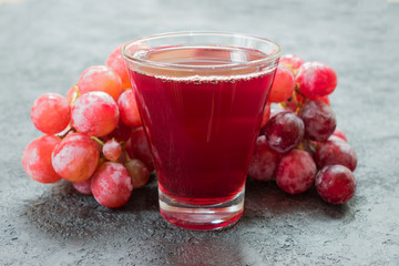 Glass of grape juice and a branch of grapes. Close-up.