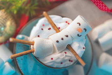 Christmas background with a marshmallow man lying in a mug with cocoa, in the background a Christmas tree with toys, a garland and gifts