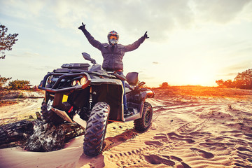 Teen riding ATV in sand dunes making a turn in the sand - obrazy, fototapety, plakaty