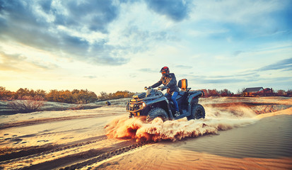 Teen riding ATV in sand dunes making a turn in the sand