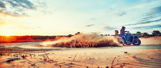 Teen riding ATV in sand dunes making a turn in the sand